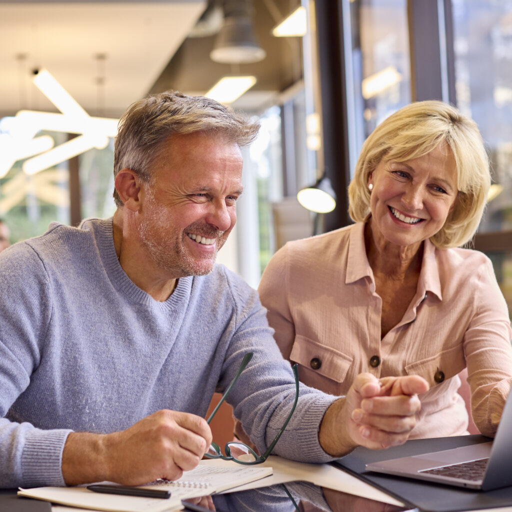 Mature Male And Female Business Colleagues Meeting Around Laptop In Modern Office